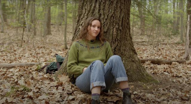 Fiona Marks sits under a tree in the woods.