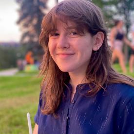 Serra Davis wears a blue shirt and has brown hair and bangs.
