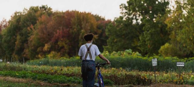 Student walks bike through the farm.