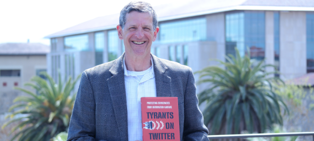 David Sloss holding his book "Tyrants on Twitter"