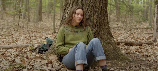 Fiona Marks sits under a tree in the woods.