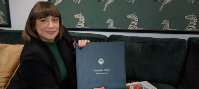 Daliza Dova looks at the camera holding up her Hampshire College diploma.