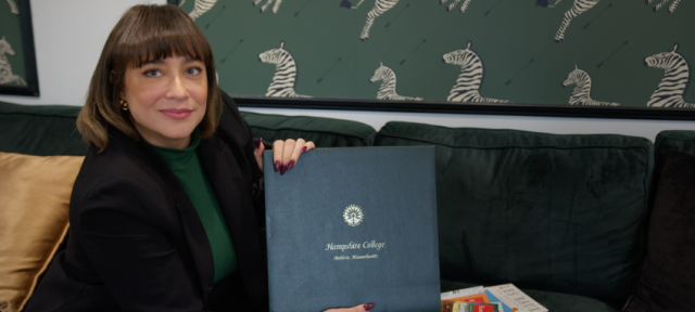 Daliza Dova looks at the camera holding up her Hampshire College diploma. 