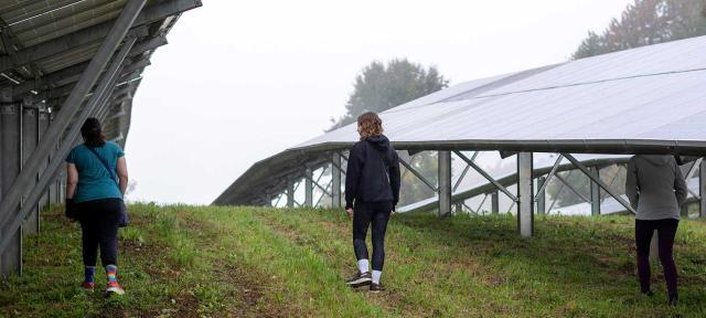 Students walk through solar panel field