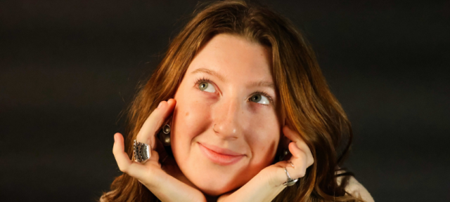 Mia Sullivan F22 smiling with her hands cupping her face.