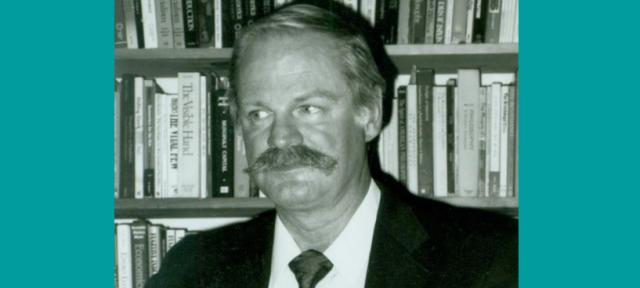 Stanley Warner in black and white in front of shelves full of books