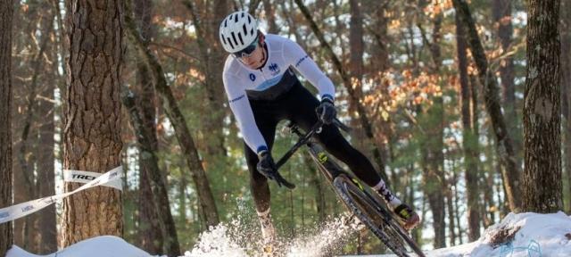 Someone riding a bike during a cyclocross race in snow.