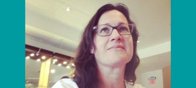 A person in glasses and a white t-shirt looking up.