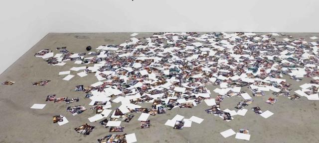 Photos scattered on a concrete floor, an installation by Anthony Discenza