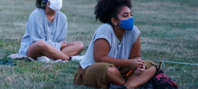 Students with masks sitting outside at new student orientation