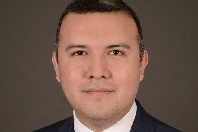 A headshot of Manny Castro in front of a plain brown background