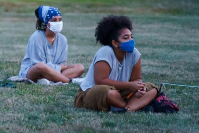 Students with masks sitting outside at new student orientation