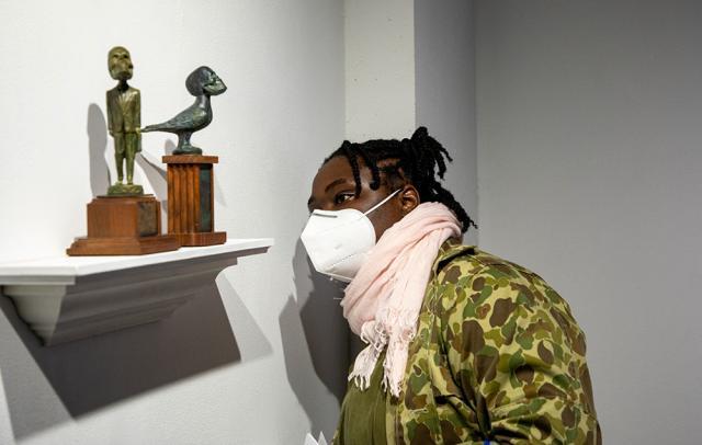 Guest looks closely at two small sculptures