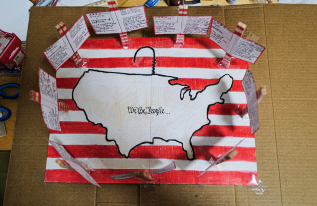 Phoebe Chen's Div II project. A map of the US surrounded by a coat hanger on a background of red and white stripes.