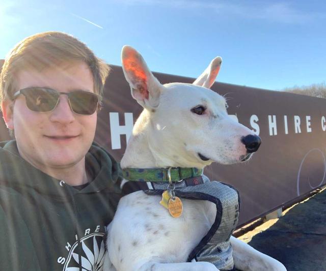 Dmitry Pepper and dog Biscuit pose in front of the Hampshire College road sign.