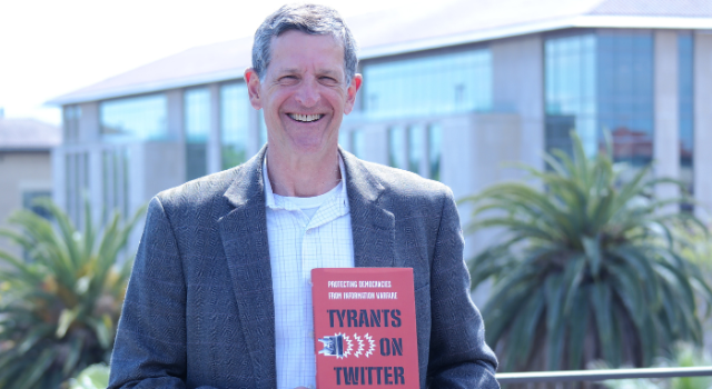 David Sloss holding his book "Tyrants on Twitter"