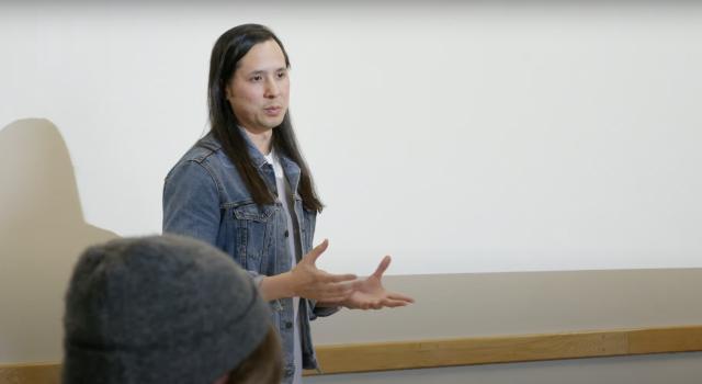 Hampshire College Professor Noah Romero standing and speaking to his class.