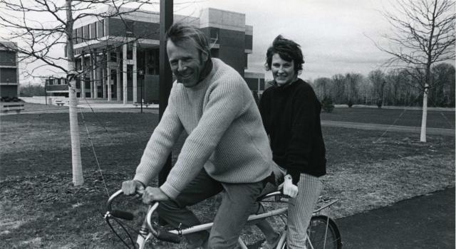 Chuck and Polly Longsworth riding a bike on the Hampshire campus