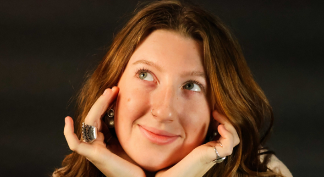Mia Sullivan F22 smiling with her hands cupping her face.