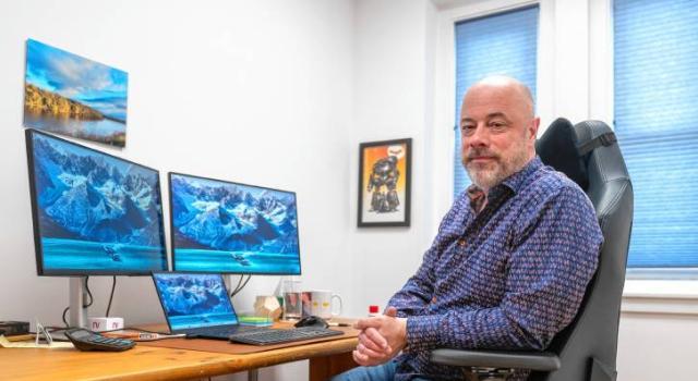 Joe Minton sitting at a desk with multiple screens