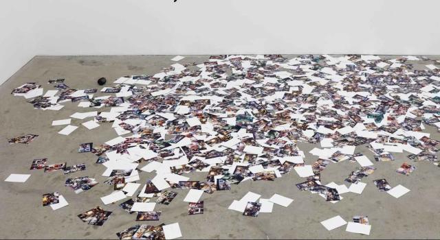 Photos scattered on a concrete floor, an installation by Anthony Discenza