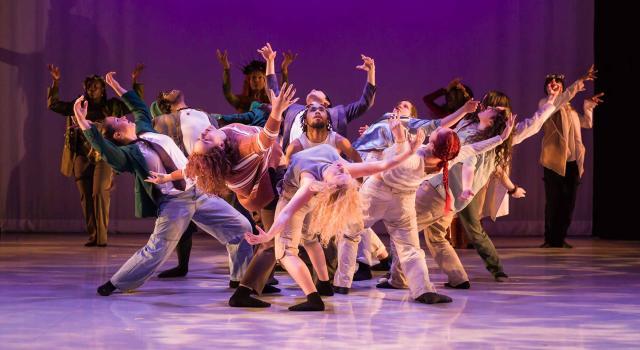 Dancers in a group leaning back with purple lighting
