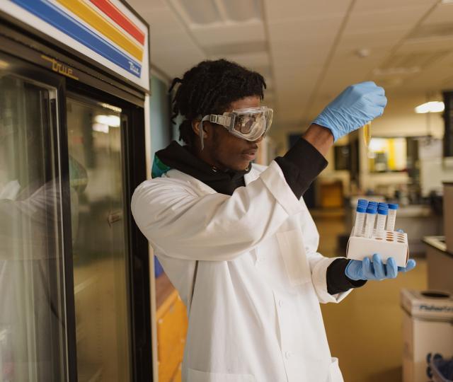 Student in science lab holds up test tube.