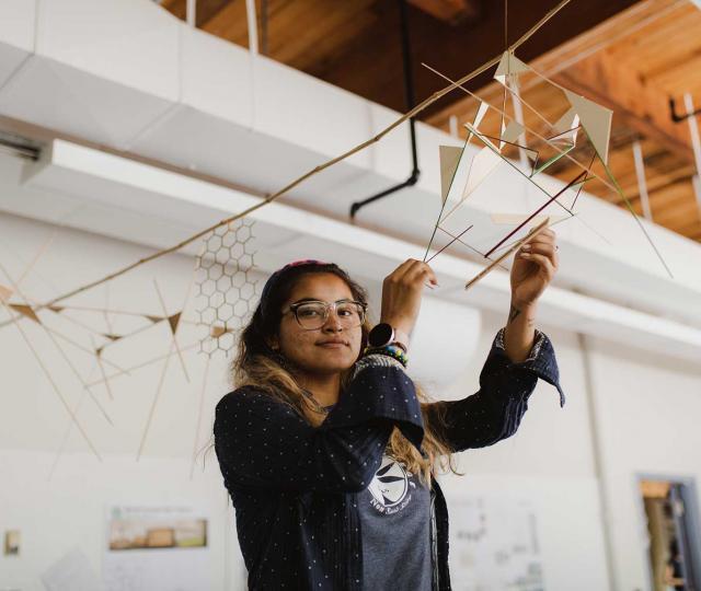 Student holding hanging sculpture.