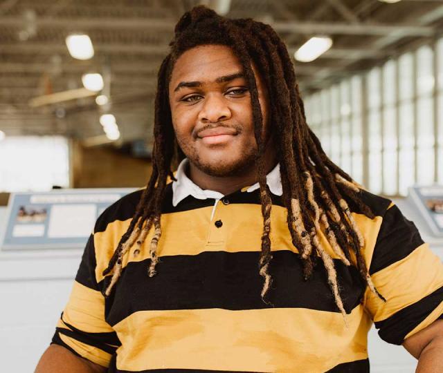 Student wearing a black and yellow shirt looks into the camera. 