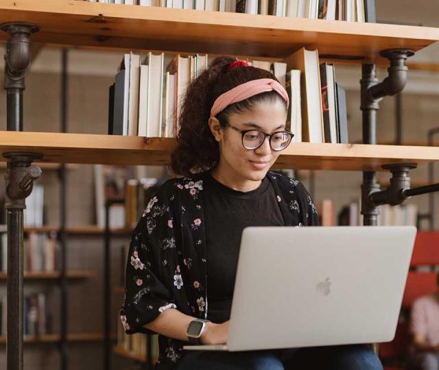 Student in library working on laptop.