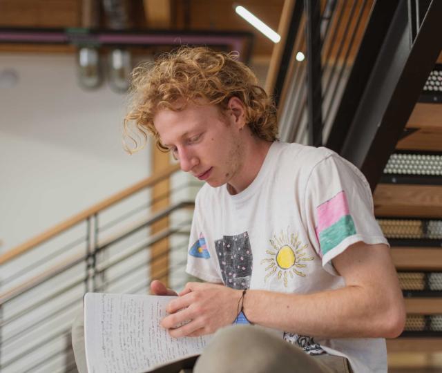 Student sitting on stairs writing in notebook.