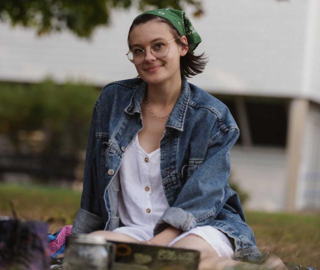 Student sitting outside on the lawn.