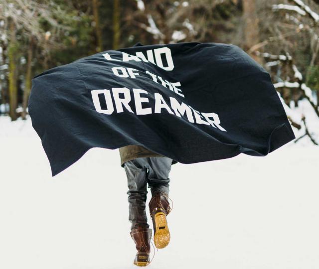 Person running with flag that says, "Land of the Dreamer."