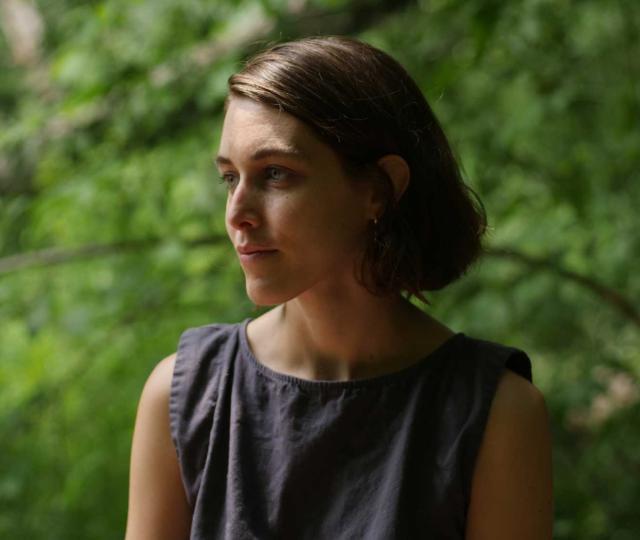 Magdalena Bermudez 10F looks off camera and is standing outside with a green leafy background.