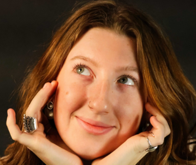 Mia Sullivan F22 smiling with her hands cupping her face.