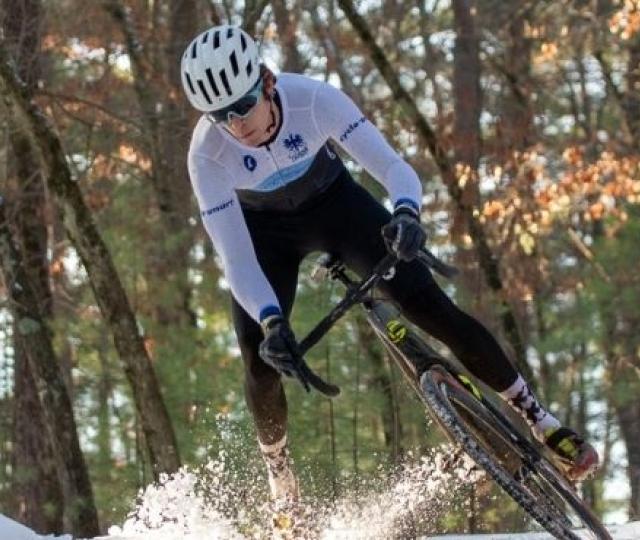 Someone riding a bike during a cyclocross race in snow.