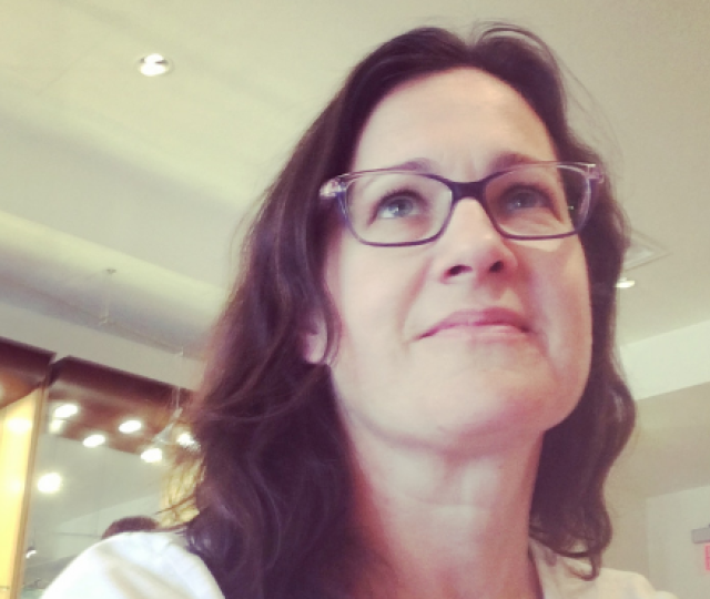 A person in glasses and a white t-shirt looking up.