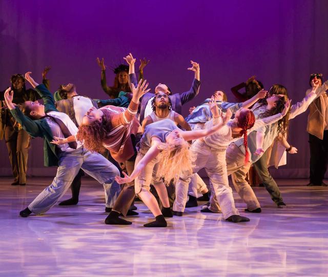 Dancers in a group leaning back with purple lighting