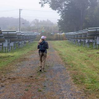 Student walks through solar panel field