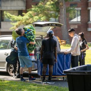 People pulling items out of a car trunk