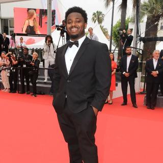 Jacory Martin, in a tux, smiling from the red carpet at Cannes Film Festival