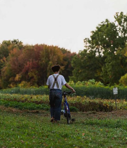 Student walks bike through the farm.
