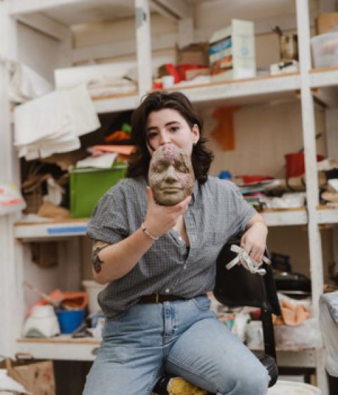 Student in Art Barn holding ceramic face