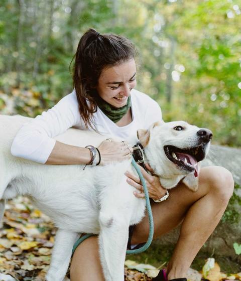 Student and dog play together in nature.