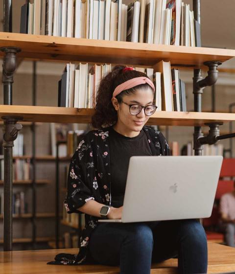 Student in library working on laptop.