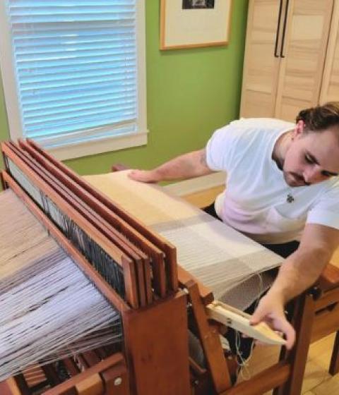 Alum Anders Zanichkowsky 04F weaving at a loom.