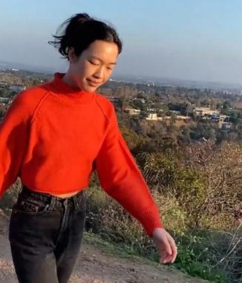 Student Daily walking on a hill in a red sweater.