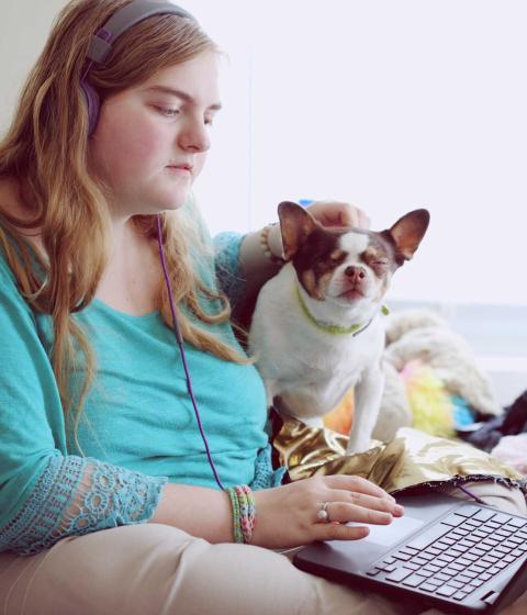 Student with service animal working on a laptop.