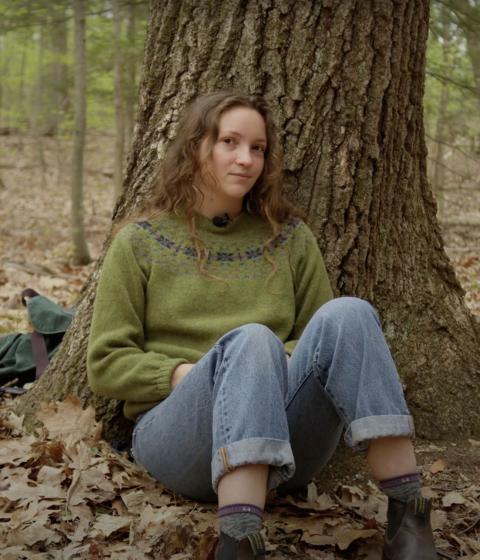 Fiona Marks sits under a tree in the woods.