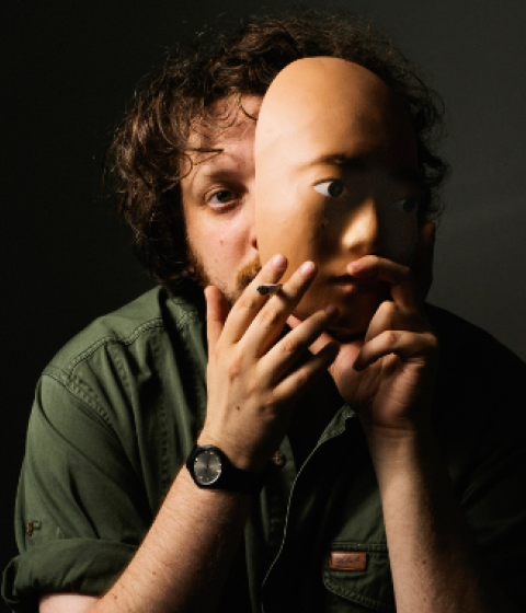 Portrait of Daniel Lopatin 00F, Oneohtrix Point Never, beside his album cover "Again."